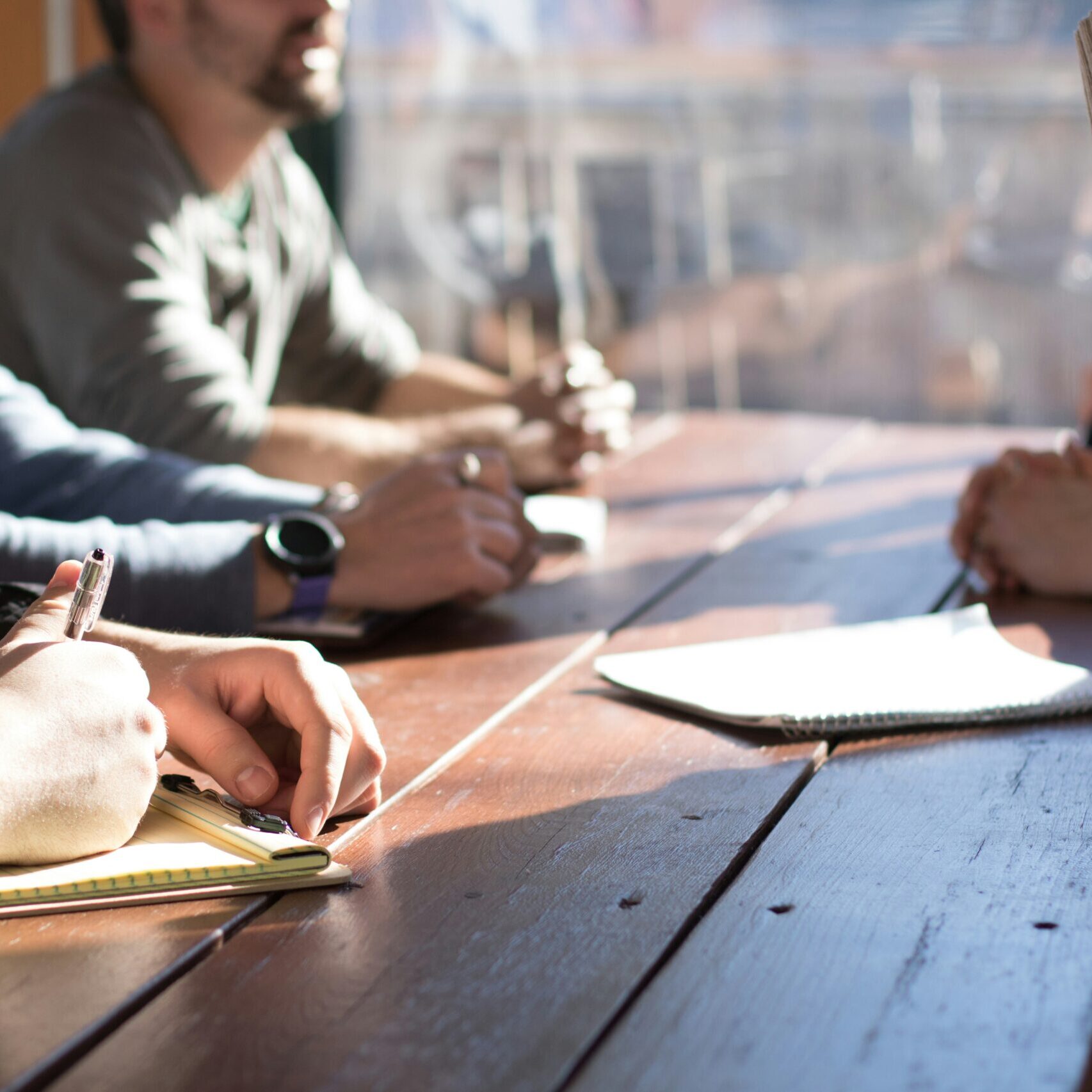 people sitting on chair in front of table while holding pens during daytime